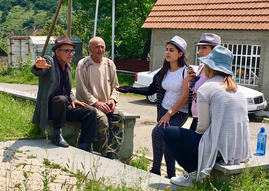 Three women and two man standing together on stairs outdoors