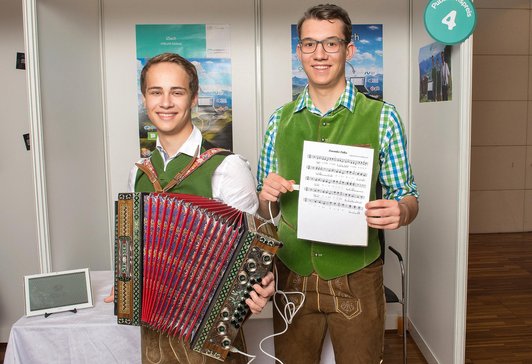 Two young men with lederhosen and one holding an accordion.