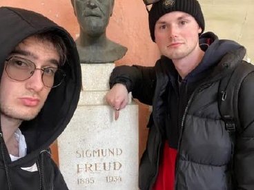 Zwei junge Männer, in der Mitte eine Büste von Sigmund Freud