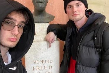 Zwei junge Männer, in der Mitte eine Büste von Sigmund Freud