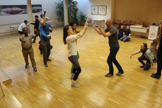 Group of people moving around together in a room 