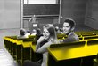 A student and a student are sitting in the lecture hall and laughing at the camera.