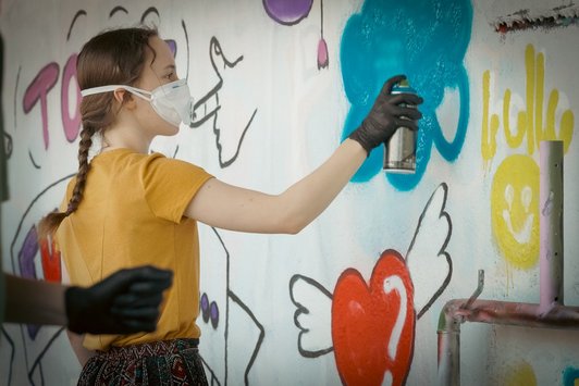 junge Menschen sprayen Graffiti auf eine Wand 