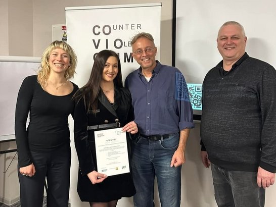 Four people standing in front of the COVIOCRIM rollup