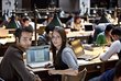 A male and female student in the reading room at the University of Vienna. Several students are studying in the background.