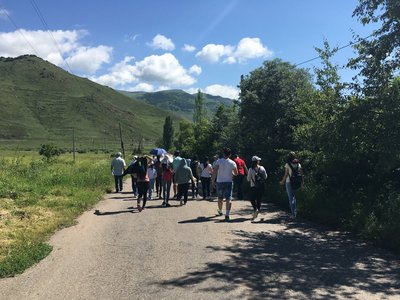 A group of people walking down a street with mountains in the background