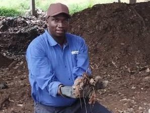 A man holding compost in his hands.