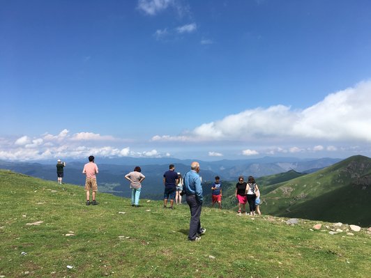 Group of people standing on a meadow on a mountain under the blue sky