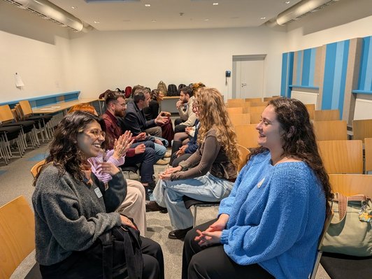 Photo of scholarship holders sitting in two rows, facing each other and engaging in a speedfriending activity