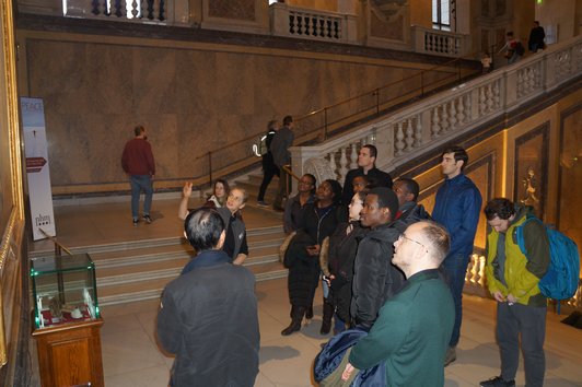 Stipendiatinnen und Stipendiaten mit der Mitarbeiterin des Naturhistorischen Museums Wien auf der Treppe des NHM Wien