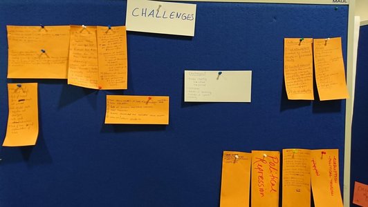 Presentation cards with handwriting on them pinned to the pin board underneath a heading that says "challenges"