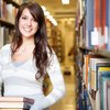 Junge Frau mit Büchern in der Hand in einer Bibliothek