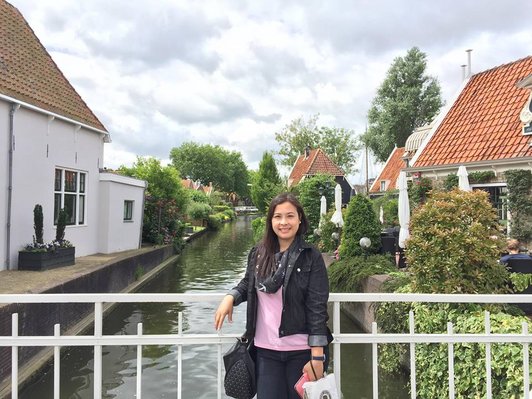 Stipendiatin Annabelle Abrera auf einer Brücke, Häuser und Bach im Hintergrund