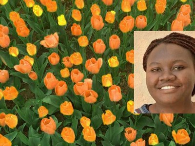 Portrait of Anne Birundi with yellow and orange tulips in the background