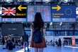 Back view of a young woman at an airport. Two signs with the inscriptions "Brexit" and "European Union" can be seen on the boards.