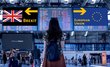 Back view of a young woman at an airport. Two signs with the inscriptions "Brexit" and "European Union" can be seen on the boards.