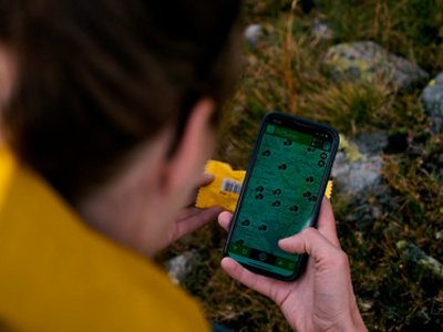 Person hält ein Stück Plastik und ein Smartphone