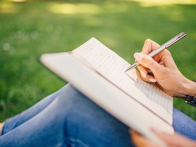 Frau schreibt in ein Notizbuch im Park