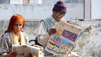 Old couple reading newspaper