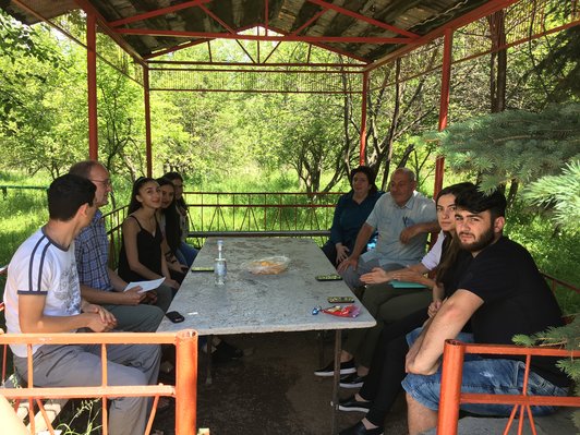 Group of people sitting at a table inmidst of green surroundings