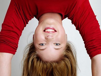 A young woman with dark blonde hair does a headstand.