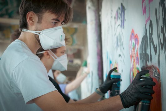 junge Menschen sprayen Graffiti auf eine Wand 