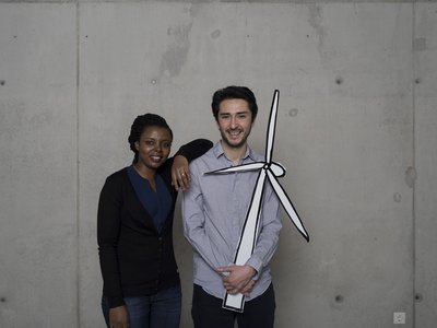 A woman and a man are holding a pinwheel recorded on cardboard.