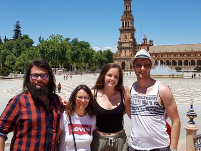  Four young people stand in front of a historic square in Málaga.