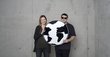 A young woman and a young man hold a cardboard globe together in their arms.