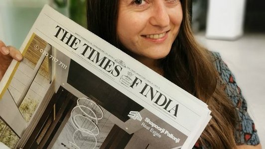 Margarita Kasper haltet eine Zeitung (The Times of Indla) in ihren Händen. Die Zeitung ist schräg und verdeckt ihren gesamten Oberkörper.