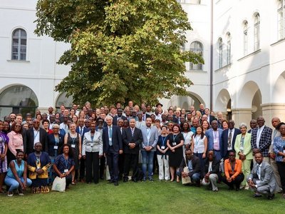 Ein Gruppenfoto in einem Innenhof. Die Mitarbeiter von Afrika-UniNet stehen auf einer Wiese, bei Sonnenschein.