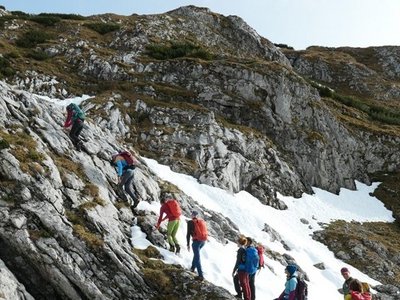 A group of hikers climbs a mountain peak