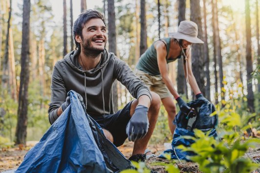 Zwei Personen sammeln Müll im Wald