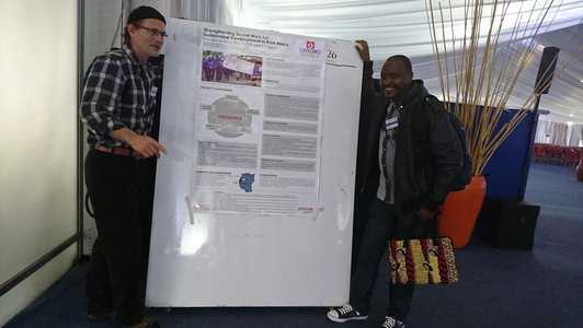 Two men standing next to a big information poster