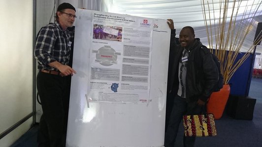 Two men standing next to a big information poster