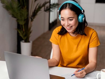 Person sitzt vor dem Laptop und trägt Kopfhörer