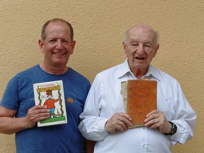 Ein Mann mit seinem älteren Vater, beide halten jeweils in Buch in der Hand