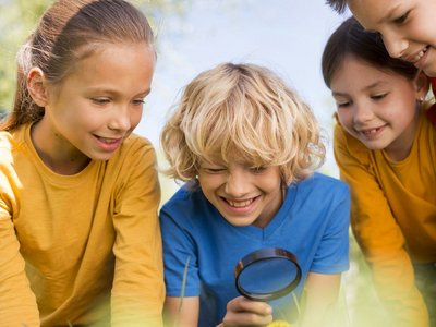 Mehrere Kinder stehen zusammen und blicken auf eine Lupe