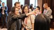 Two alumni take a selfie with the managing director of the OeAD Jakob Calice. In the background, other people can be seen blurred in small groups.