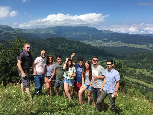 Group of people posing for a group picture in green landscape