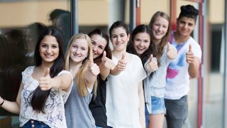 Eine Gruppe junger Menschen schaut in die Kamera und gibt ein Daumen hoch.