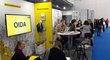  The Austrian trade fair stand with tables and chairs on which visitors and representatives from Austrian universities sit.