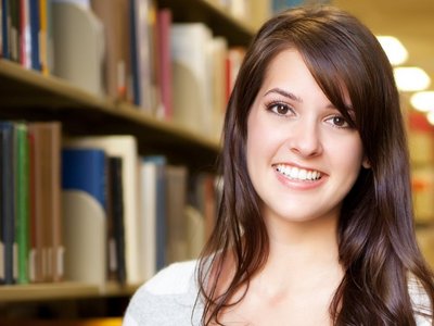 Studentin befindet sich in der Bibliothek und hält Bücher in der Hand