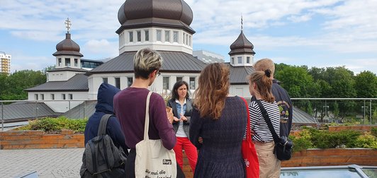 Studenten bei einer Stadtführung durch Lemberg mit einer Führerin vor einer Sehenswürdigkeit.