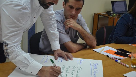 Two people looking at a poster on which one man is writing something