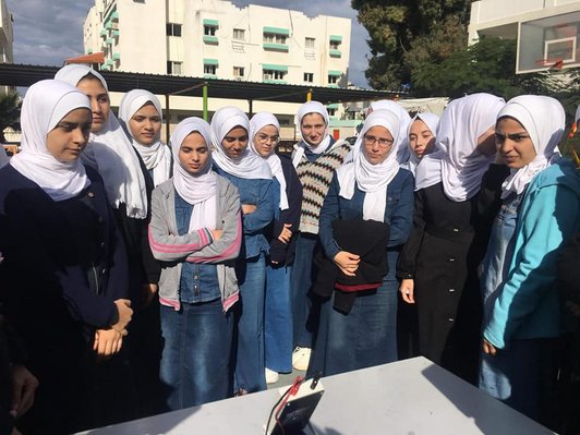 Female high school students inspect solar panel at high school yard