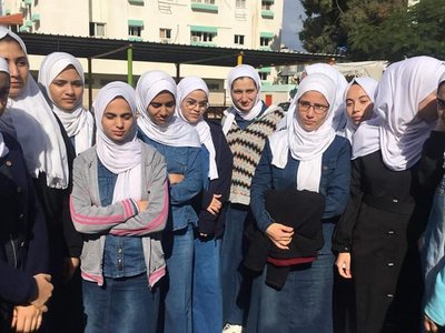 Female high school students inspect solar panel at high school yard