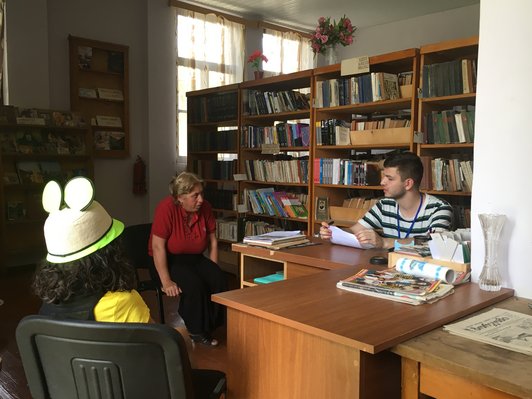 Three people are sitting in a library.