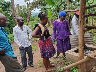 People looking at how a farmer demonstrates how he processes fertilizer from the waste from his pigsty.