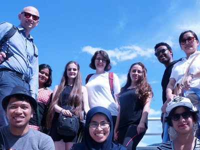 A group of ten people standing and sitting on what looks like an observation platform in the countryside